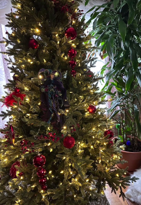 A close view of deep red ornaments and warm lights on evergreen branches